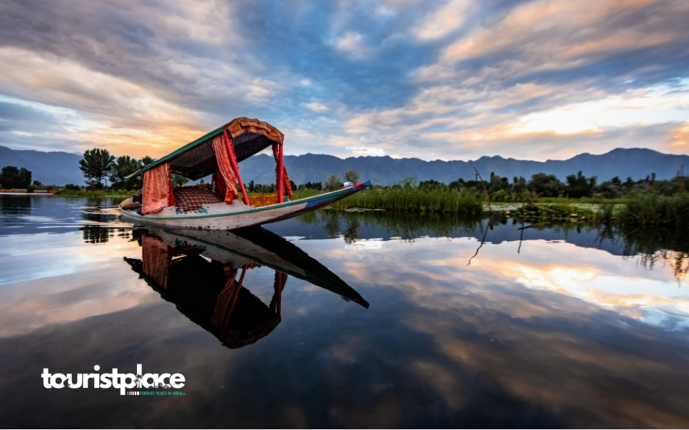 Shikara boat floating on Dal Lake in Srinagar surrounded by mountains during sunset - Tourist Place In India